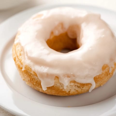 A close-up of fluffy, glazed yeast donuts with a glistening, white coating, ready to enjoy.