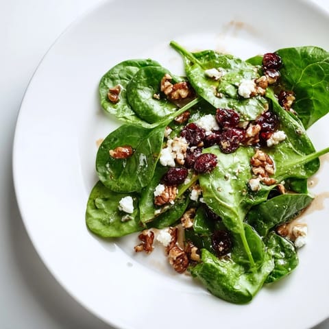 A vibrant spinach goat cheese salad topped with crunchy candied pecans and drizzled with tangy balsamic vinaigrette.