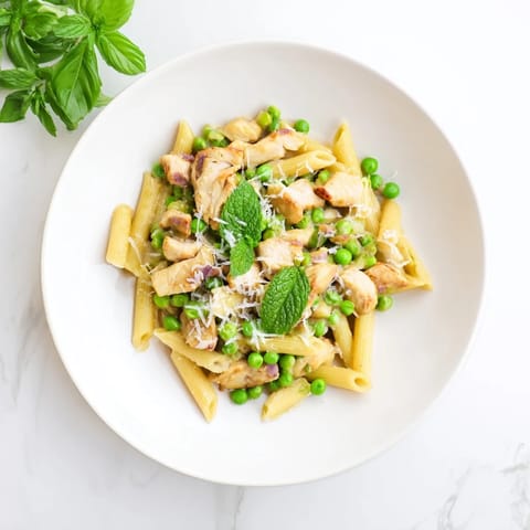 Bright green peas and tender chicken pieces nestle in penne pasta, all coated in a glossy lemon-herb sauce flecked with fresh mint.  