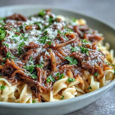 Tender beef and rich gravy from Crockpot French Onion Pot Roast Pasta ladled over wide egg noodles.