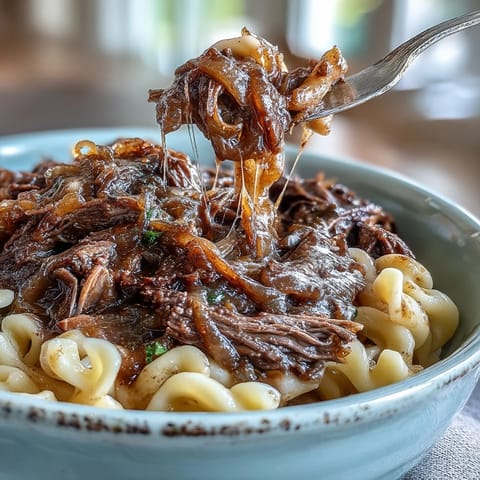 Savory shredded beef and caramelized onions smother buttery noodles in this comforting Crockpot French Onion Pot Roast Pasta dish.