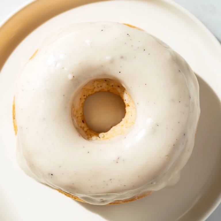 Freshly baked muffin tin donuts covered in sweet, creamy glaze offer a comforting delight.