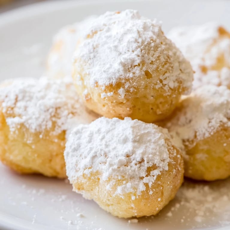 Warm, sweet zeppole dusted with powdered sugar, a traditional Italian-American treat with a perfect bite.