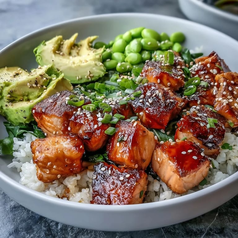 Ready-to-eat Salmon Rice Bowl features tender salmon, crisp cucumber slices, and a spicy sriracha mayo drizzle on warm jasmine rice.